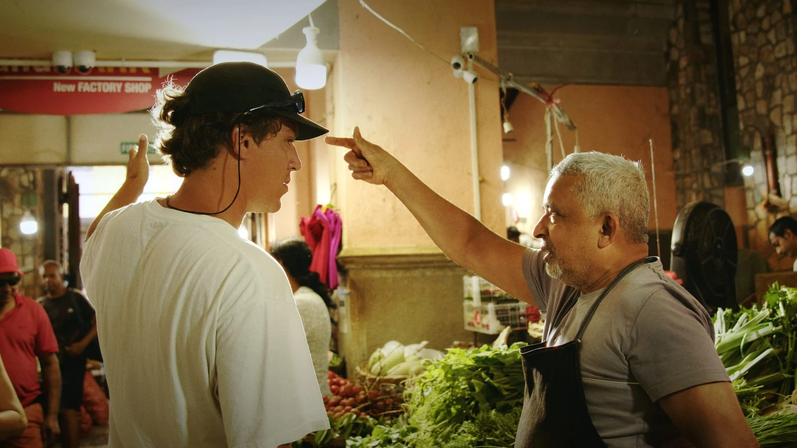 Two people talking beside vegetable stalls in a Mauritian market, from Groundwork